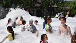 Children having fun in a foam party outdoors during summer.