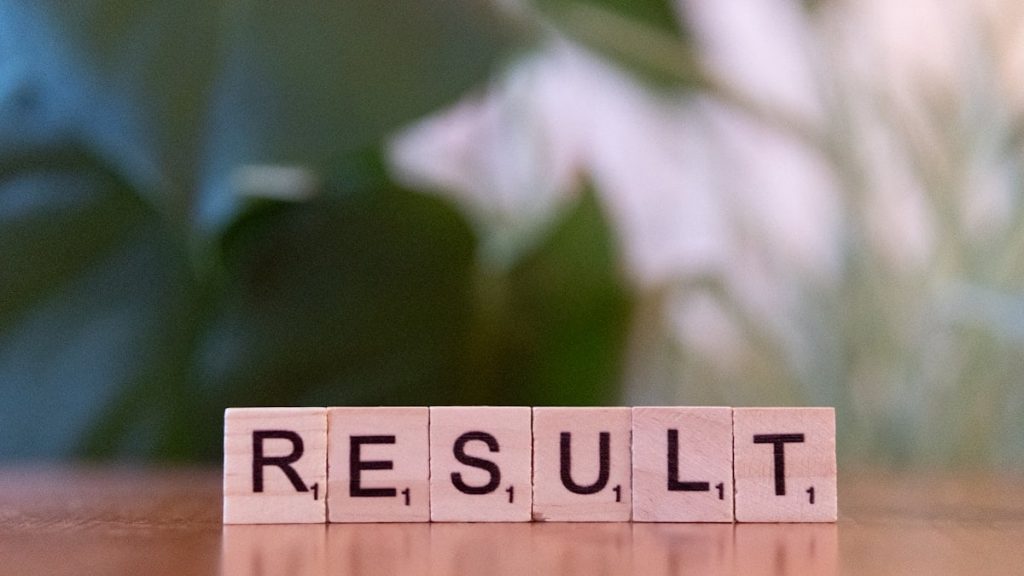 A wooden block spelling the word result on a table